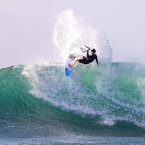Chico surfeando en una ola con el kitesurf
