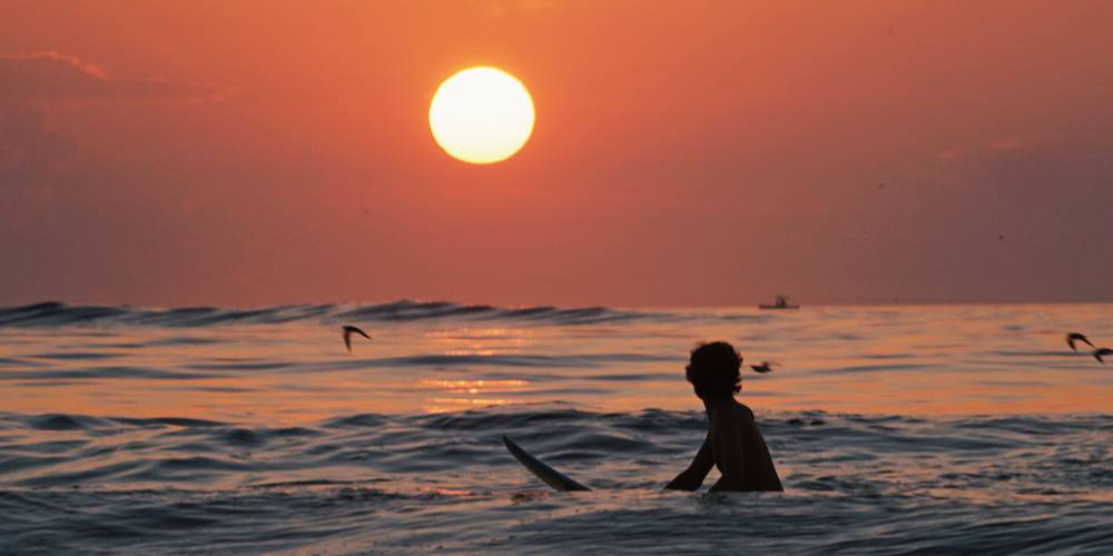 Surfero al atardecer en el agua