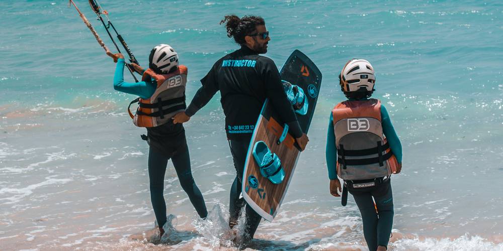 Monitor de kitesurf con niño en playa
