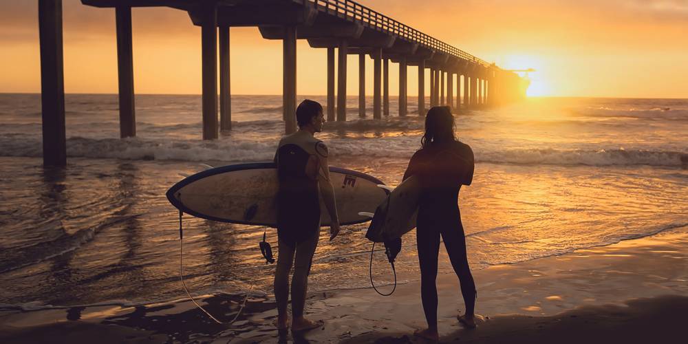 Surferos viendo atardecer debajo de puente